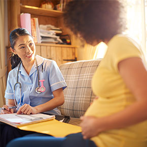 midwife and expectant mother sitting on couch discuss files
