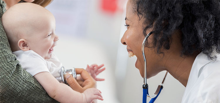 midwife listening to heart of smiling baby