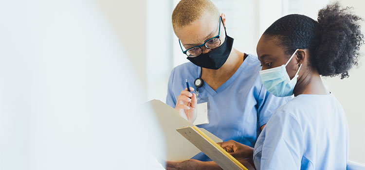 two nurses looking at medical charts together in medical facility