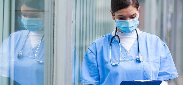 nurse in mask examining clipboard