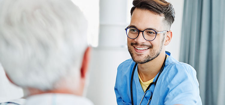 smiling male nurse consoles elderly male patient