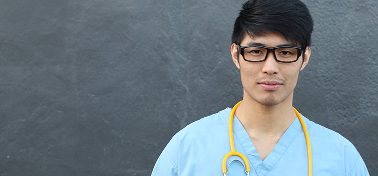 male nurse stands against stark wall