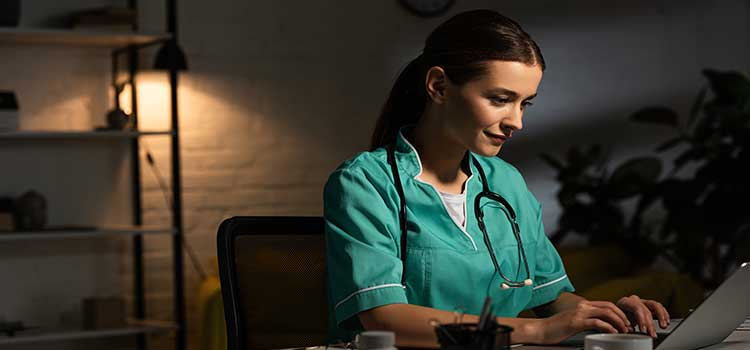 nurse studying in darkened room by lamp
