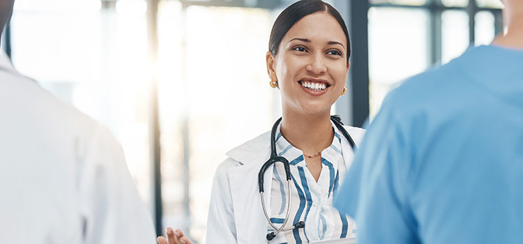smiling nurse manager works with two nurses to review hospital protocol
