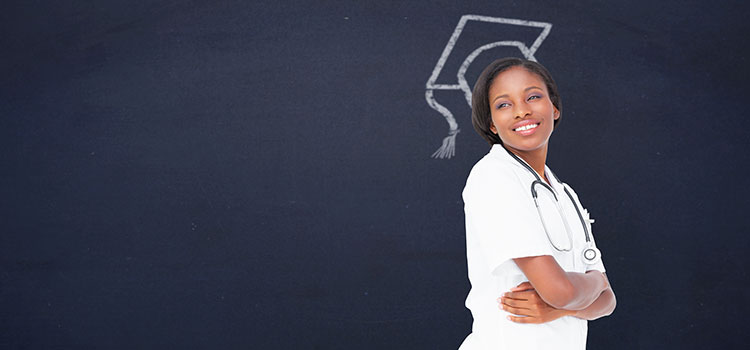 female nurse smiles with arms crossed with a chalkboard graduation cap on