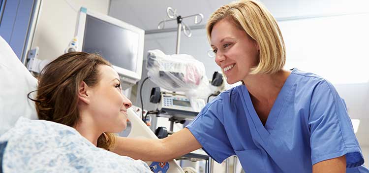 nurse speaks with patient that is in a hospital bed