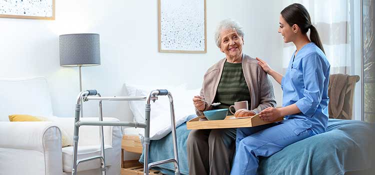 nurse practitioner brings lunch to senior in nursing home