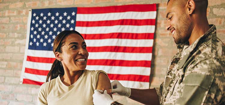 military nurse puts bandage on gi shot site