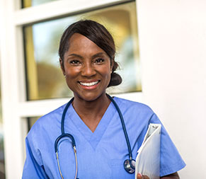 a middle-aged female nurse stands outside of a healthcare building